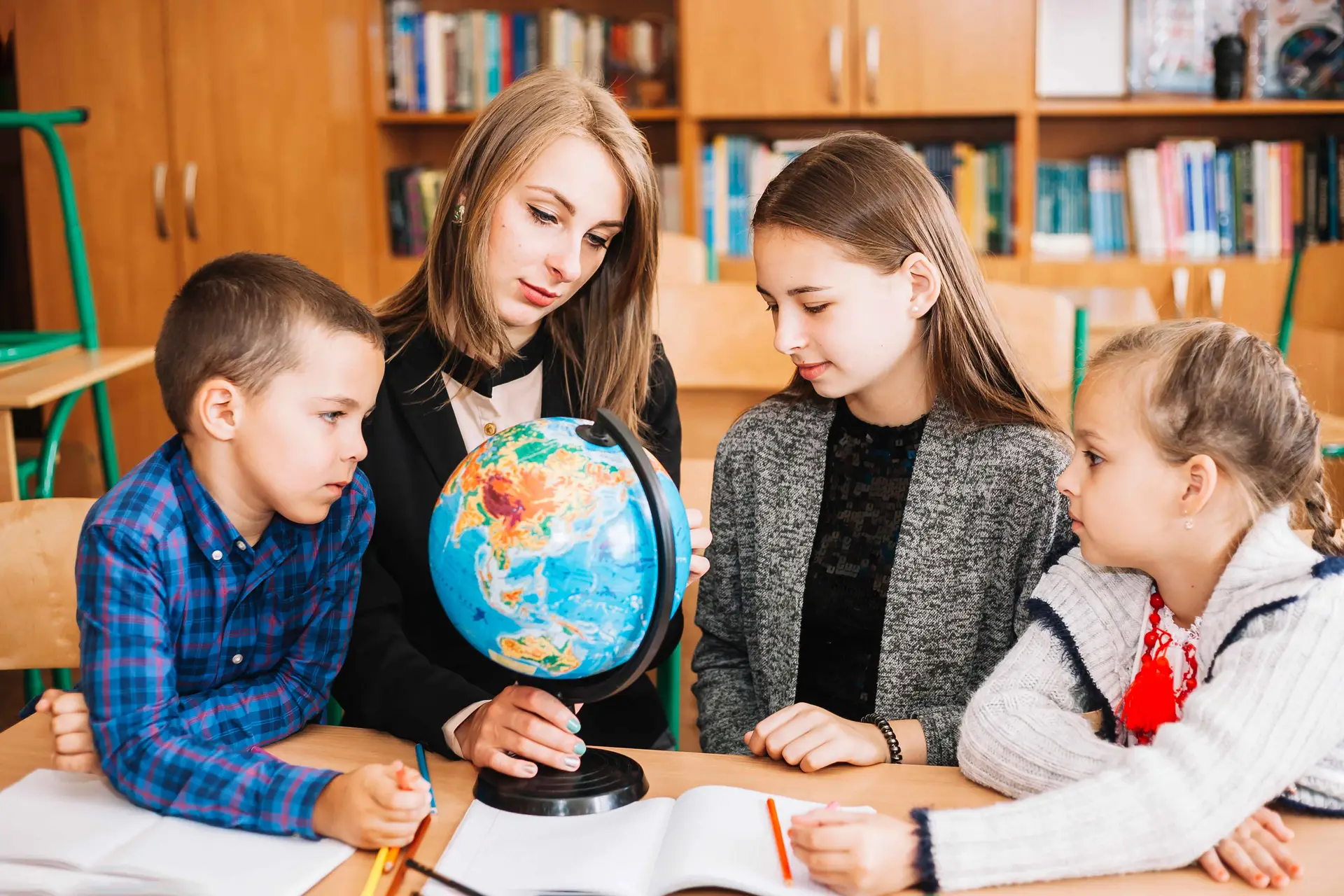young-woman-teaching-geography-pupil-with-globe